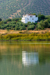 Fototapeta na wymiar Spanish lake with reflection of a white house and olive groves.