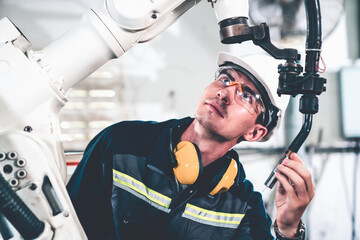 Young factory worker working with adept robotic arm in a workshop . Industry robot programming...