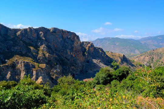 Grassy mountain with crolling clouds and blue sky.