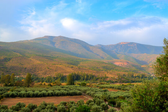 Grassy mountain with crolling clouds and blue sky.