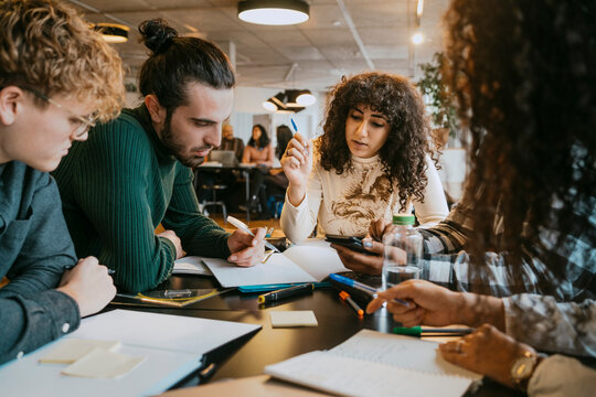 Students studying together at table in cafeteria