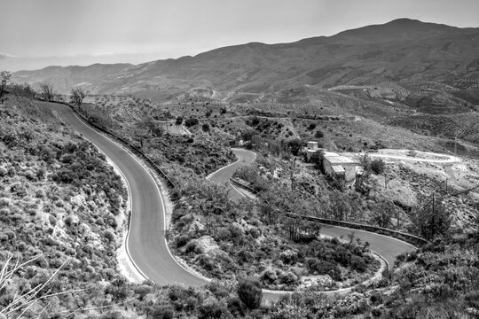 Very windy country road up a Spanish hill. Twisty switchback. Monochrome, black and white