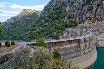Curving hydro electric dam with road on top and sheer rock face in the background