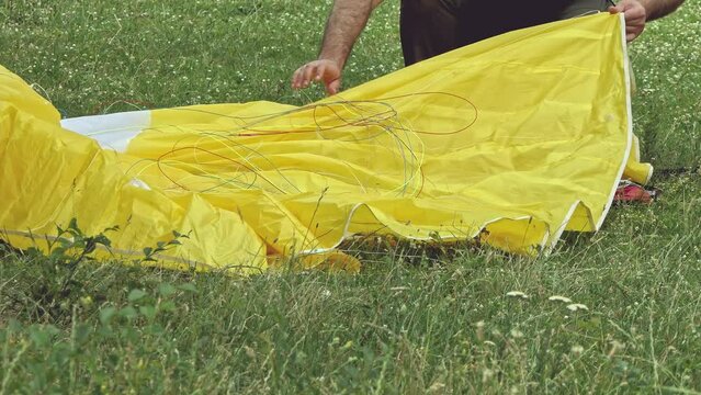 A parachutist folds a paraglider on a meadow. Summer afternoon. Extreme sport