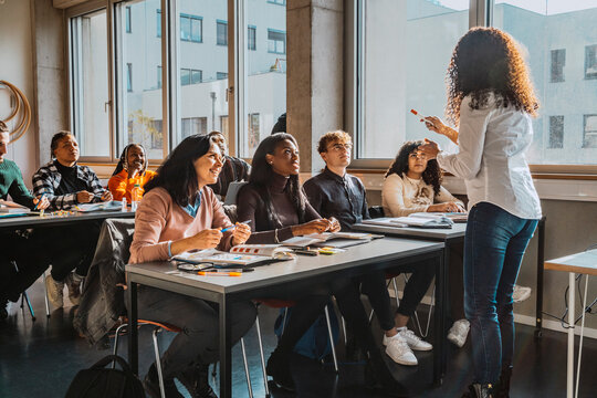Professor explaining multiracial university students sitting in classroom