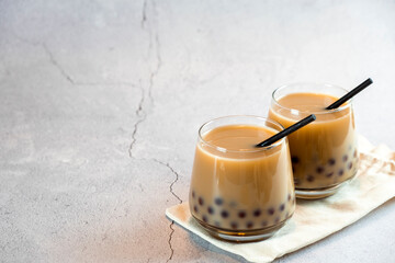 Two glasses with milk bubble tea with delicious tapioca pearls. Famous Taiwan milk jelly tea. Tasty drinks with copy space.