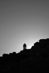 Obraz premium Amazing golden sunset and silhouette view of churches and the village of Imerovigli in Santoriniin black and white 