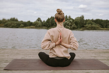 Young woman doing yoga by the lake.   Fitness relaxation stress-free concept. 