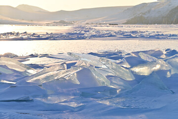 transparent ice on Lake Baikal at sunset in winter. Ice floes on the shore at sunset.