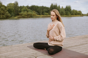 Young woman doing yoga by the lake.   Pose balance, meditation.