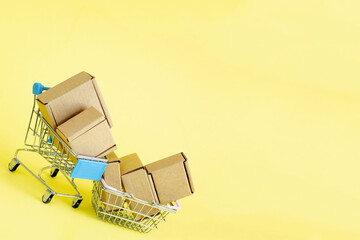 Paper shopping bags in a shopping cart on yellow background, concept online shopping.