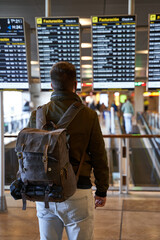 young digital nomad with a backpack looks at the flight schedule
