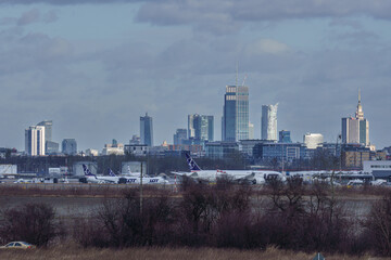 Passenger planes of the airline against the background of skyscrapers in the center of Warsaw.
