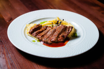 Grilled meat with sauce and mashed potatoes side view.