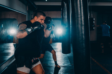 Fit professionalkick  boxing man kicking at punching bag