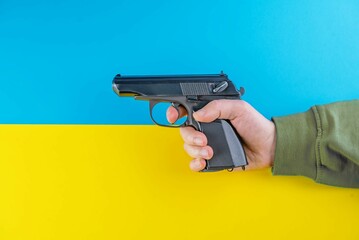 Blue and yellow flag of Ukraine and a hand with a gun