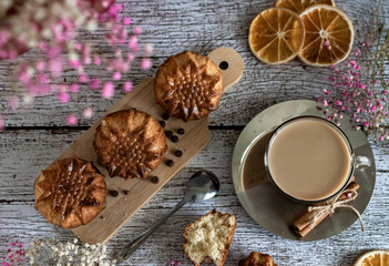 Flat lay delicious holiday breakfast homemade muffins and cup of latte coffee on wooden light background, closeup