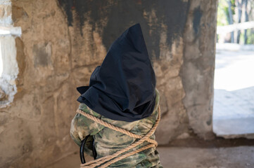 Caucasian woman is taken hostage tied with a rope and with a black bag on her head. 