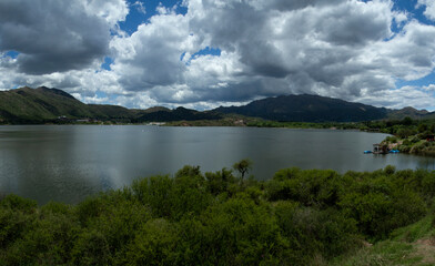 Panorama view of the reservoir Potrero de los Funes in San Luis, Argentina. The green forest, hills and lake under a dramatic sky with beautiful clouds.