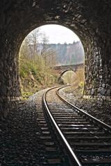 Fototapeta na wymiar Exit of Vintage train stone tunnel with view on a stone bridge. England style railway travel.