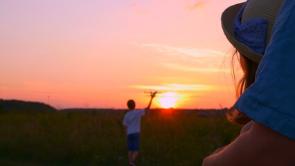 A happy family spend time together at sunset in the backyard, mom stands in an embrace with her...
