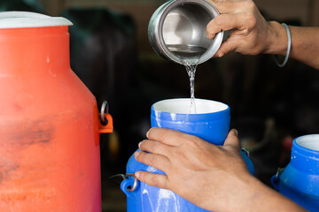 Close up shot, milk dairy farmer mixing water into milk container at farmhouse - conept of Milk Adulteration, and contamination.