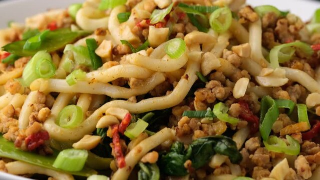 Pork, peanut noodles with pak choi, mangetout and red chili. Asian food. Rotating video