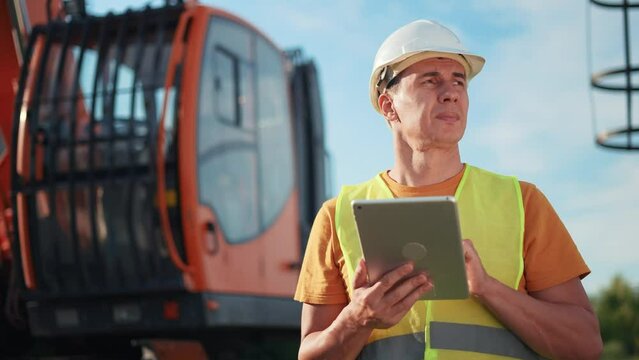 worker in hard a hat with digital tablet near excavator. construction site driver with online digital tablet. industry construction concept. worker hard business hat near excavator truck in uniform.