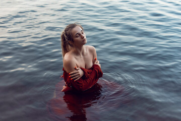Fototapeta premium Blonde girl bathes in a summer lake