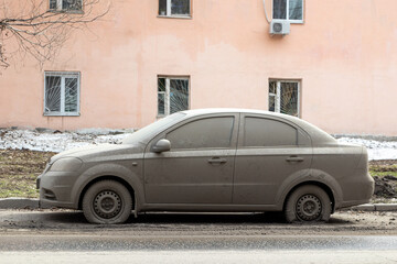 Passenger car completely covered with dirt on a spring city street