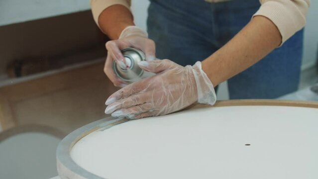 Spraying silver paint on the round frame of the canvas