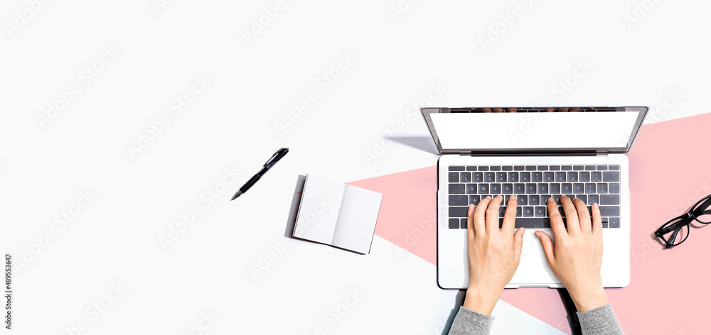 Aufkleber person using a laptop computer with a notebook and eyeglasses - flat lay