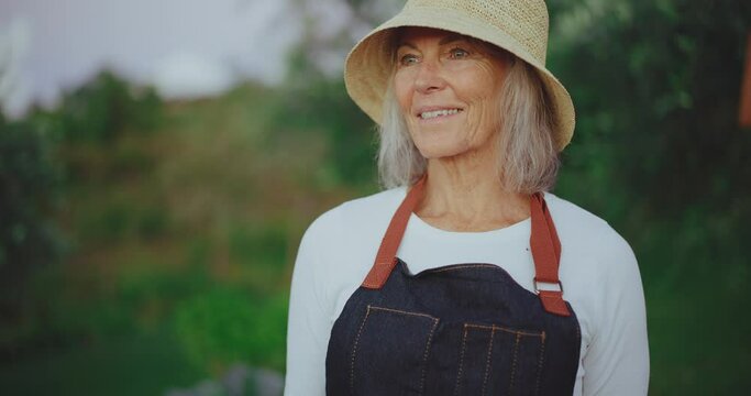 Portrait of happy mature woman in her 60s smiling, tending to her garden in the golden years of retirement