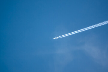 looking up at a Dutch KLM Airbus A330-300 twin engine jet airliner en route to the USA in deep blue sky as it moves diagonolly across the frame