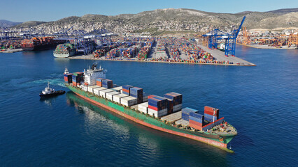 Aerial drone photo of huge container ship leaving logistics and container terminal of Perama,...