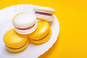 Sweet and bright banana and currant macarons on a white plate. French dessert.