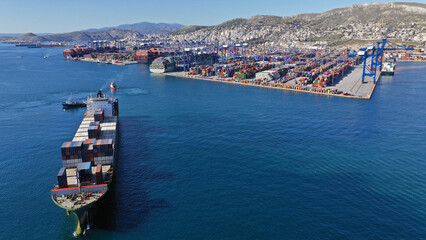 Aerial drone photo of container vessel leaving industrial loading - unloading logistics container terminal area of Perama, Attica, Greece