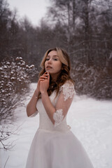 Fototapeta na wymiar girl in a white dress in the snow in winter