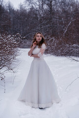 Obraz na płótnie Canvas girl in a white dress in the snow in winter