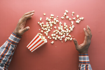 hand reaching for popcorn on red background 