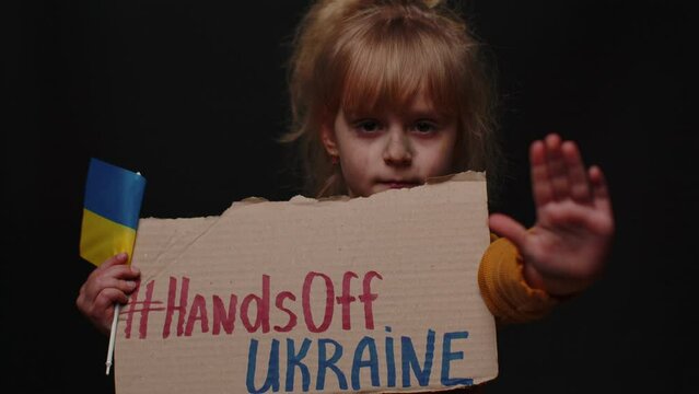Portrait of homeless Ukrainian girl child kid in dirty torn clothes showing inscription massage text on map Hands Off Ukraine. Asking Stop aggression from Russia country. Crisis, war, no peace, help