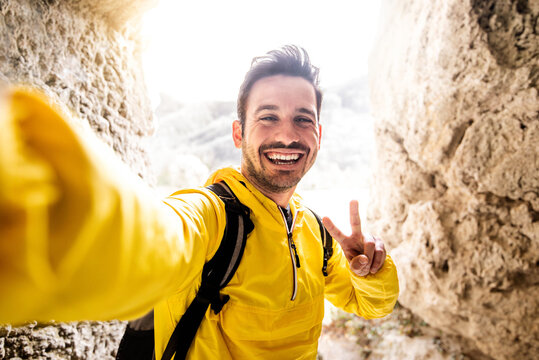 Man with backpack taking selfie pic hiking on mountains - Hiker walking on extreme rocks - Sport and active lifestyle concept