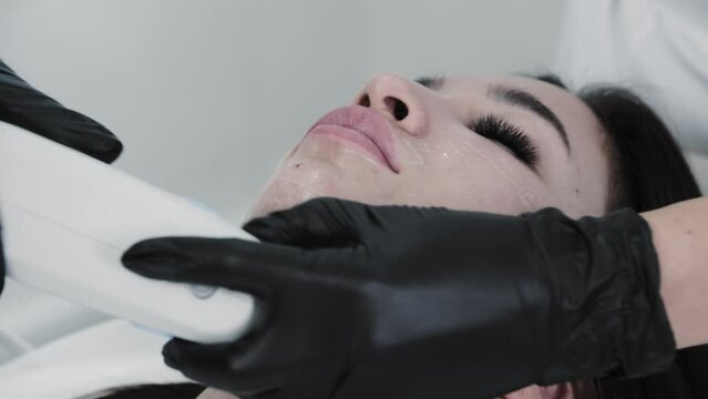 The therapist uses an electric device under the chin of her female client