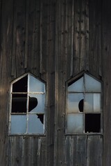 Broken old windows on a wooden barn. The tooth of time or the reflection of war.