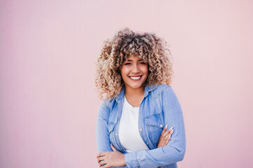 portrait of smiling hispanic woman with afro hair in city.spring. Arms crossed.Urban lifestyle