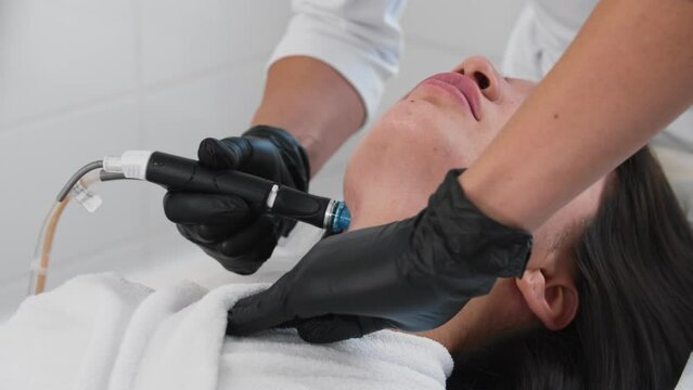 Young brunette woman getting electric procedures on her neck