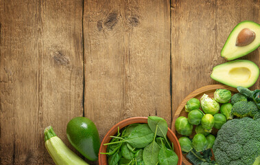 Green vegetables selection on wooden background. Top view, copy space.