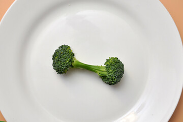 Green broccoli on a dumbbell-shaped plate. The symbol of proper nutrition