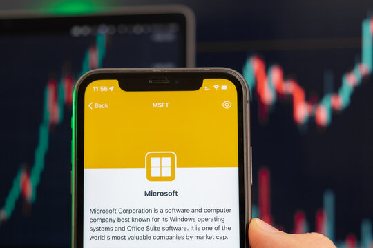 Microsoft stock price increasing on the trading market with uptrend line graph bar chart on the background. Man holding a mobile phone with company logo, February 2022, San Francisco, USA
