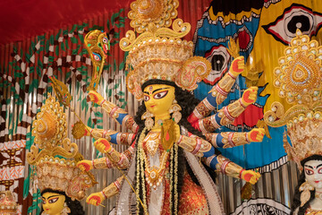 Goddess Durga idol at decorated Durga Puja pandal, shot at colored light, at Kolkata, West Bengal,...